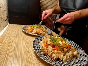 European gay chef strips and cooks noodles with chicken and vegetables.